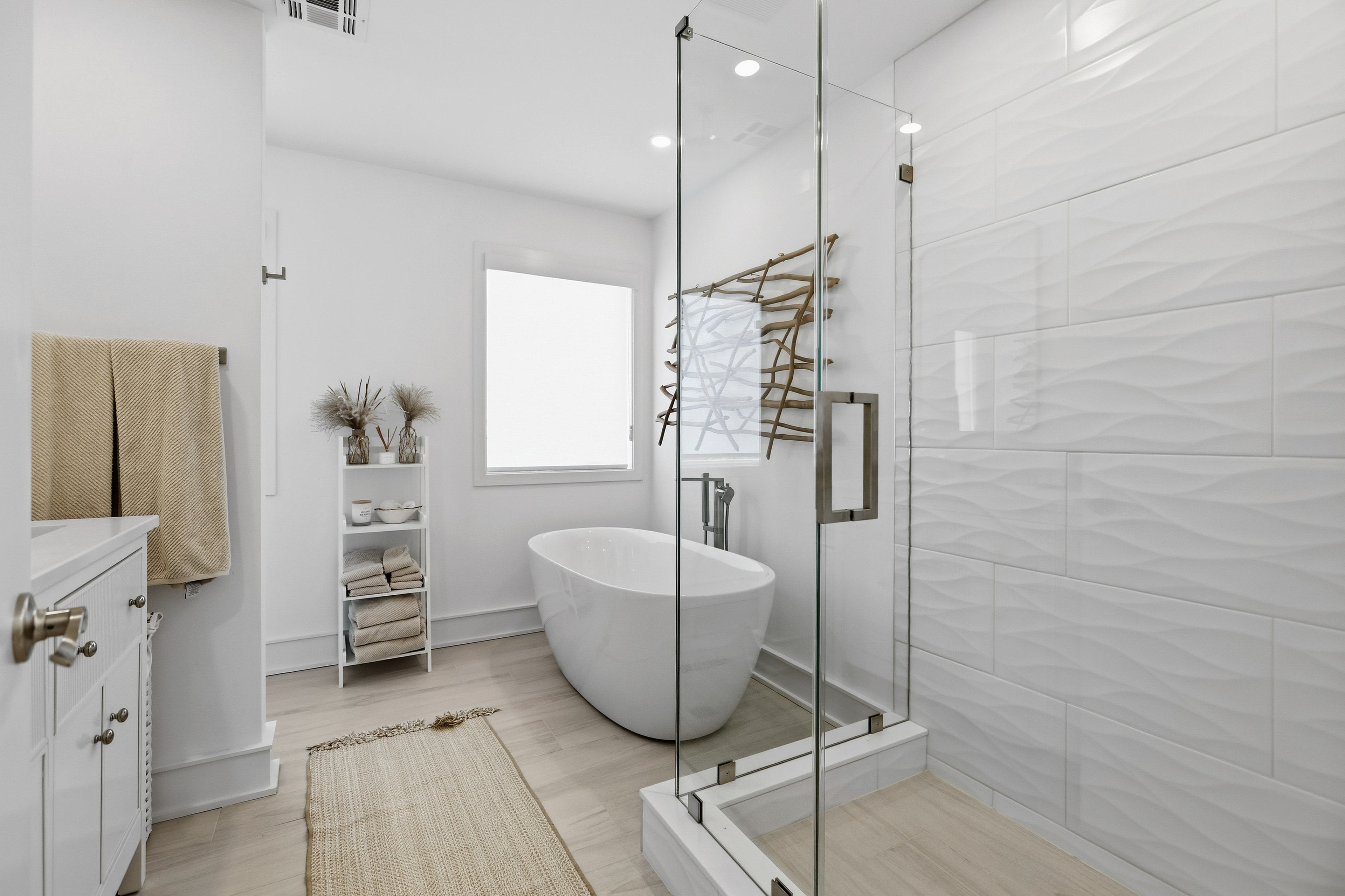 Master bathroom with freestanding soaking tub, glass shower, and wave-tile walls