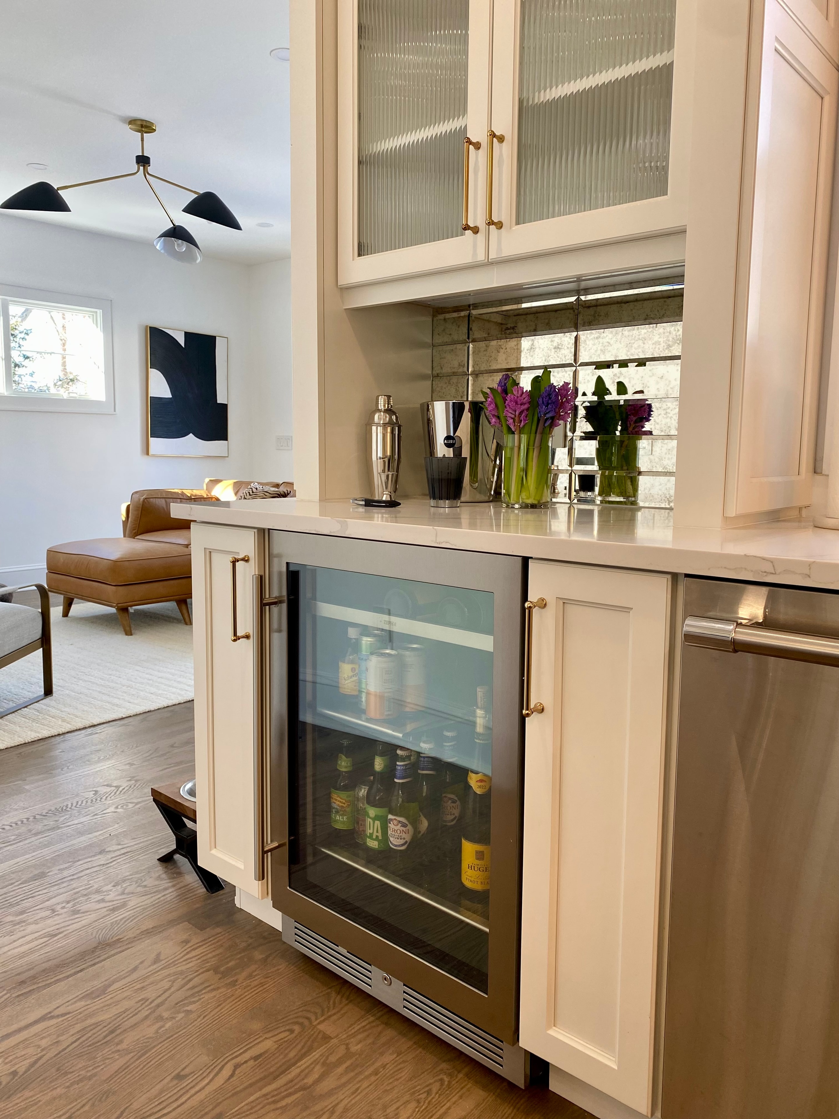 Built-in mini bar with beverage cooler, antique mirror backsplash, and brass hardware