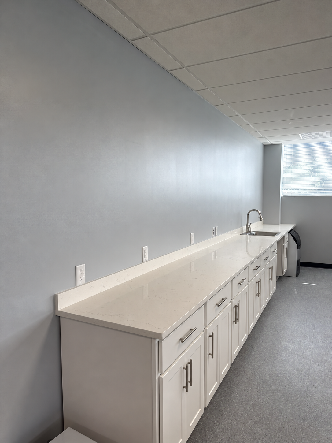 S2S laboratory center break room kitchenette with white cabinetry and quartz countertops